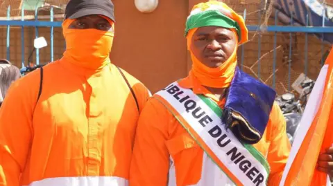 Getty Images Citizens of Niger dressed in nationals perform Friday prayers and afterwards celebrate the departure of French troops in front of the French military base in the capital Niamey, Niger on 29 December 2023