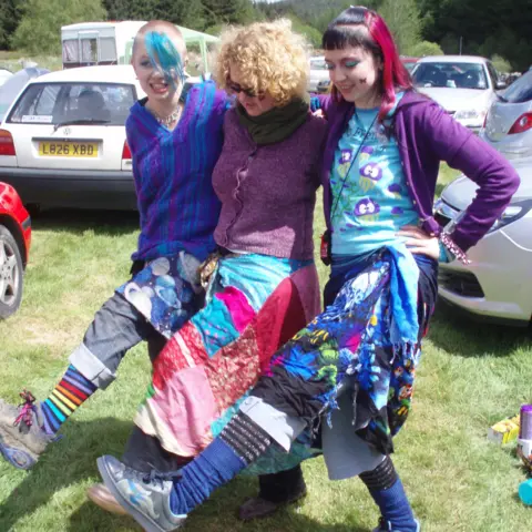 Tricia Hayes Tricia Hayes with her daughters, Stacey and Steff, kicking up their legs. They are wearing very colourful clothes.