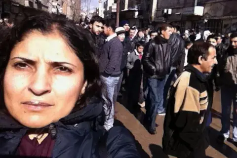 Lina Sinjab, a Syrian BBC journalist in a photo taken in Ein Tarma, eastern Damascus, in 2012, with a crowd of men behind her