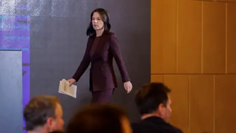 Reuters German Foreign Minister Annalena Baerbock arrives for a press conference in China wearing a purple suit and carrying her papers