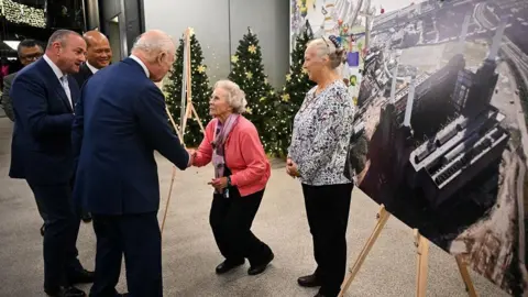 Getty Images An elderly woman curtseys as she shakes King Charles's hand, as others look on