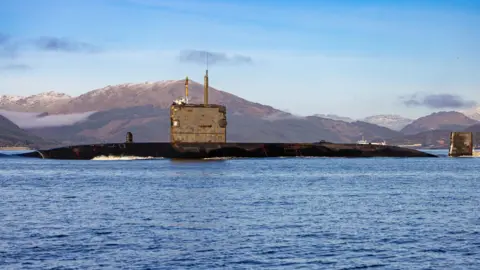 Royal Navy HMS Triumph at sea on a bright sunny day with blue skies and clear blue water