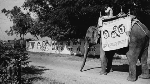 Getty Images An elephant bearing the red triangle symbol of the Lal Tikon Fund to publicise birth control and family planning, enters a village to spread the news and offer information