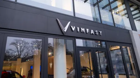 Getty Images The front of a car showroom with black-framed windows and the words Vinfast in silver lettering above the doors