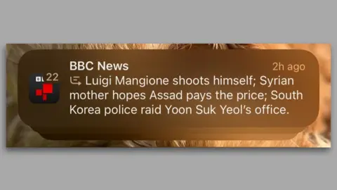 BBC News A zoomed in phone screenshot of the misleading BBC notification from an iPhone. It reads: "BBC News, Luigi Mangione shoots himself; Syrian mother hopes Assad pays the price; South Korea police raid Yoon Suk Yeol's office".