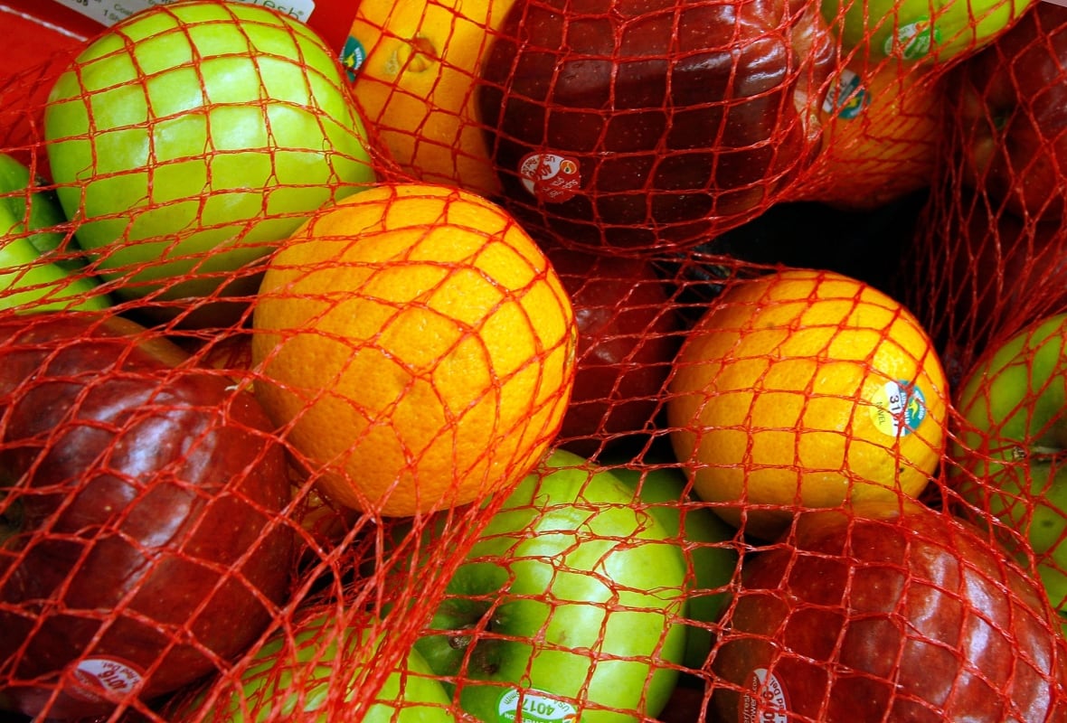 Apples and oranges in a net in a grocery store.