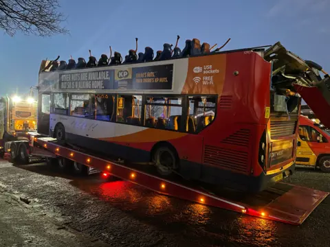 A roofless double decker Stageboach bus being loaded onto the back of a lorry