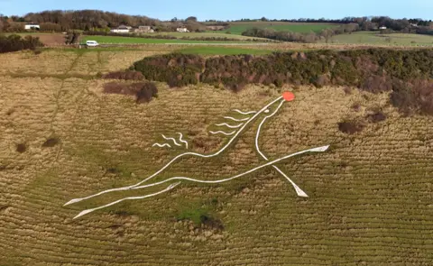 Gareth Fuller/PA Media A view of the White Horse, carved into Cheriton Hill, near Folkestone, Kent,  but with a round red nose, depicting the legendary Rudolph, the red-nosed reindeer.
