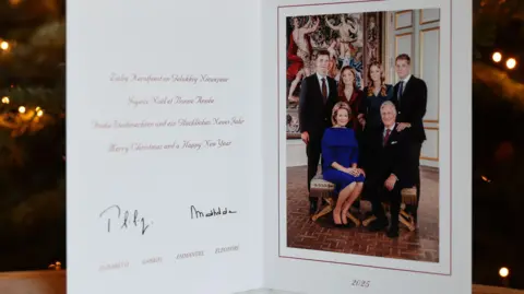 The Belgian royal family's Christmas card, dated 2025, features the family sitting and standing formally indoors, in front of a large painting. The message is in Dutch, French, Flemish and English and says: Merry Christmas and a Happy New Year. 