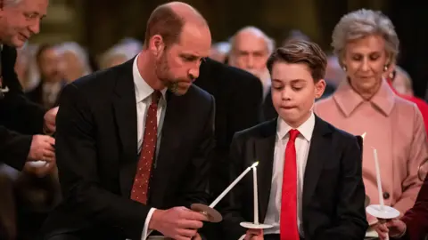 PA Media The Prince of Wales helps his son Prince George light a candle during the Together At Christmas carol service at Westminster Abbey