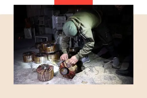 Getty Images A treated image shows a men inspect electrical storage components,there are pills across the floor