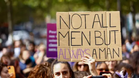 Reuters A woman holds a sign saying Not All Men but Always a Man