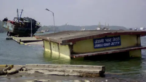 Getty Images A picture taken 28 December, 2004 shows a flooded coastal jetty in Port Blair, the capital city of India's southeastern Andaman and Nicobar Islands state. Huge waves triggered by an earthquake 26 December, killed at least 4,000 people on the islands leaving thousands of people missing and countless numbers homeless in India as the death toll crossed 8,500 from a tsunami that slammed into unprotected coasts across Asia. 