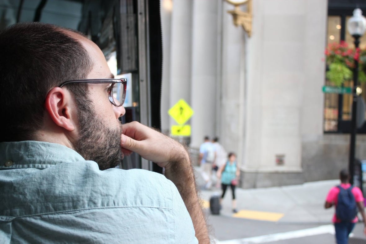 A man with a beard is photographed, pensively from behind.