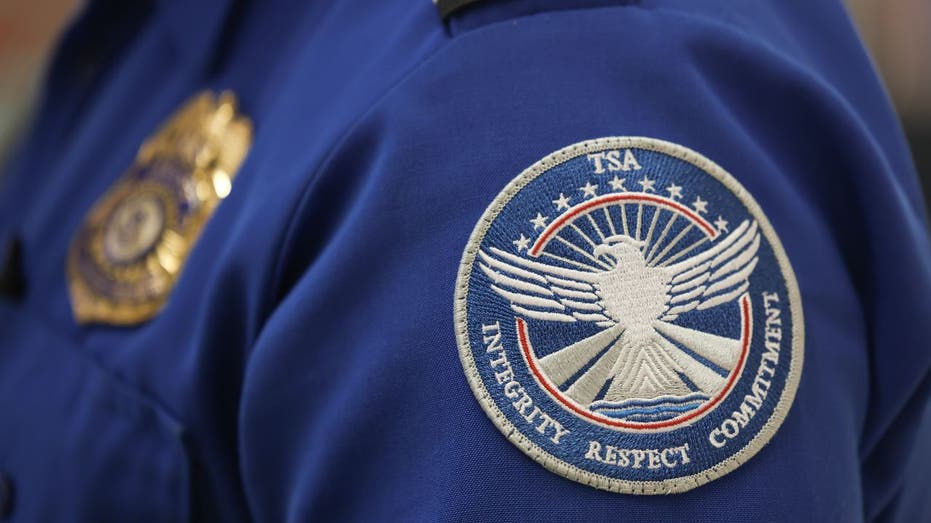 A TSA agent wears a patch on his uniform.