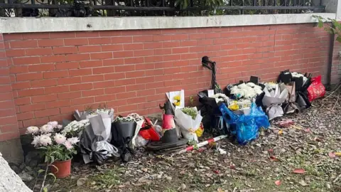 Reuters Floral tributes are placed near an entrance to the Wuxi Vocational College of Arts and Technology following a knife attack, in Wuxi, Jiangsu province