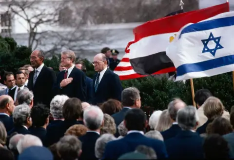 Getty Images Egyptian President Anwar El-Sadat, US President Jimmy Carter, and Israeli Prime Minister Menachem Begin as they stand for their respective national anthems on the North Lawn of the White House, Washington DC, March 26, 1979. Following the Camp David Accord, they were there to sign the Egypt-Israel Peace Treaty.