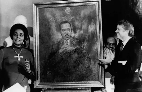 AP Coretta Scott King, widow of slain civil rights leader Dr. Martin Luther King, Jr., speaks at an unveiling of a portrait of Dr. King by artist George Mandus, Feb. 18, 1974, and dedicated by Gov. Jimmy Carter. It is the first portrait of an African American to be represented in the state's official portrait gallery.