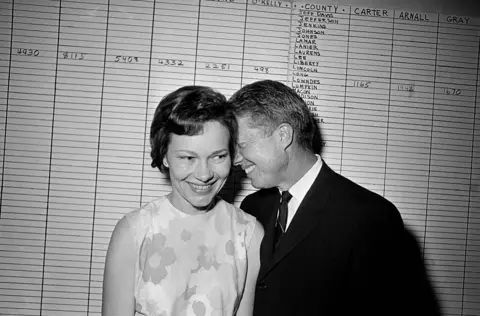 AP In this Sept. 15, 1966 file photo, then Georgia State Sen. Jimmy Carter hugs his wife, Rosalynn, at his Atlanta campaign headquarters.