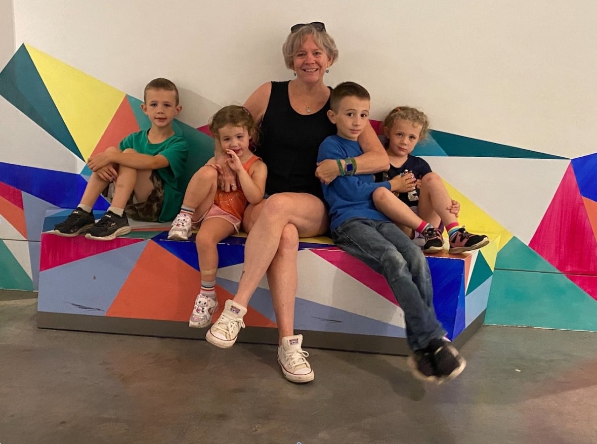 An older woman sits on blocks with four young kids.