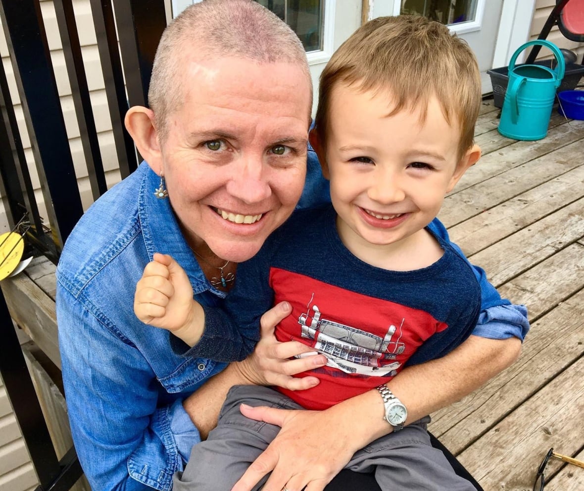 A woman with short hair holds a young boy.