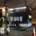 Roof torn off bus after crashing into railway bridge