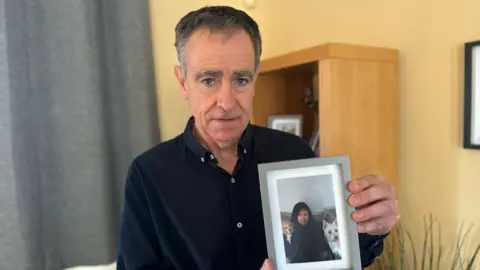 Josie Hannett/BBC Pete holding an image of his daughter Hannah