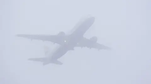 PA Media A plane takes off in misty conditions from London Gatwick airport in Crawley, West Sussex.