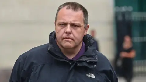 Pacemaker Neil Beckett wearing a black North Face coat with a purple top as he leaves court.