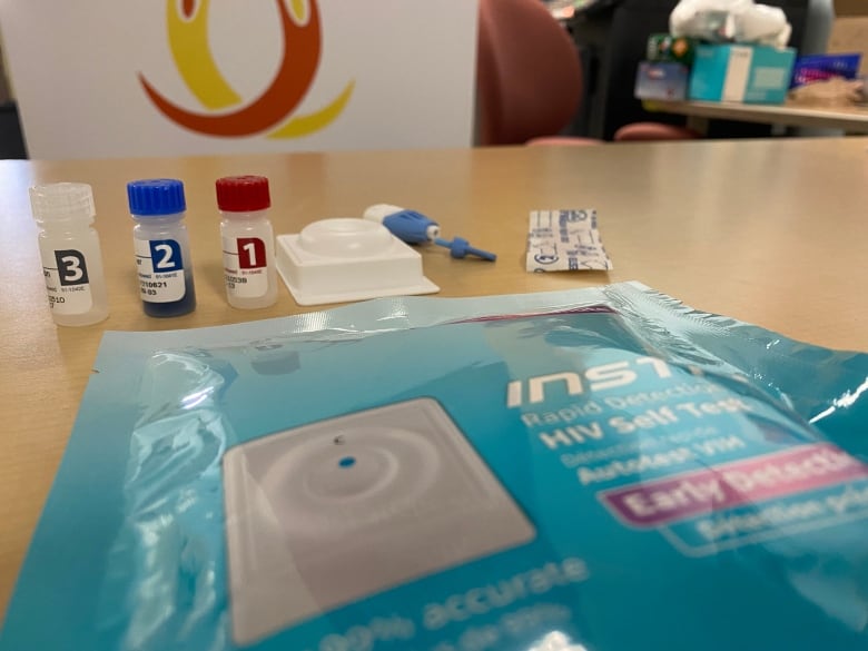 Three vials and other equipment for an HIV self-testing are laid out on a wooden surface.