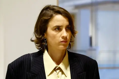 Reuters A headshot of Adele Haenel. She has short brown hair and wears a black suit jacket and yellow shirt.