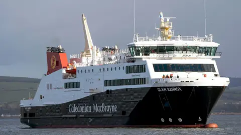 PA Media A black and white ship with red funnels with Caledonian MacBrayne written the side, sailing on the River Clyde with hills in the background