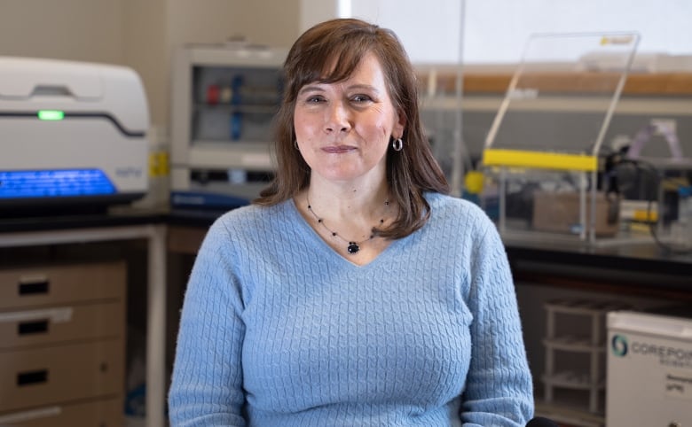 A woman poses for a picture in a lab.