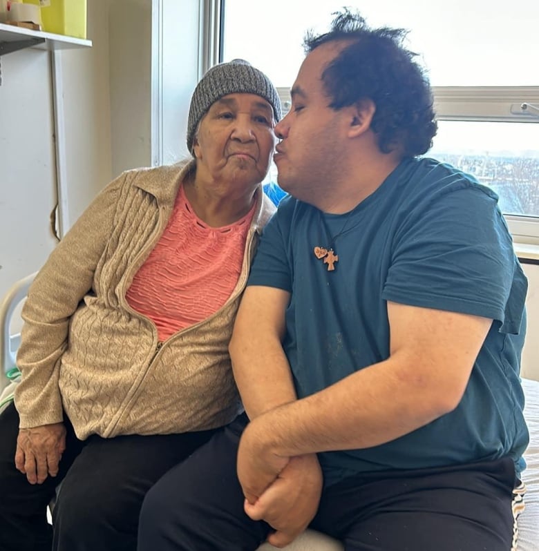 A man kisses an older woman on the cheek. 