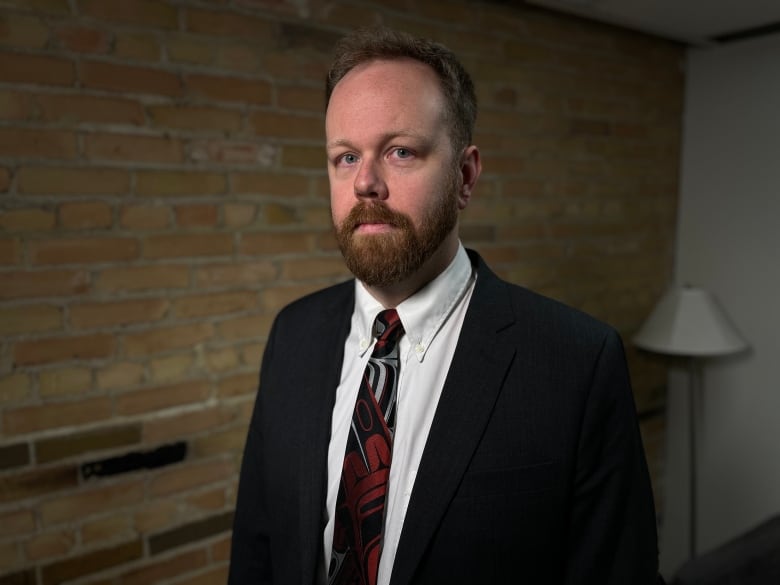 A man in a suit and tie with brown hair.