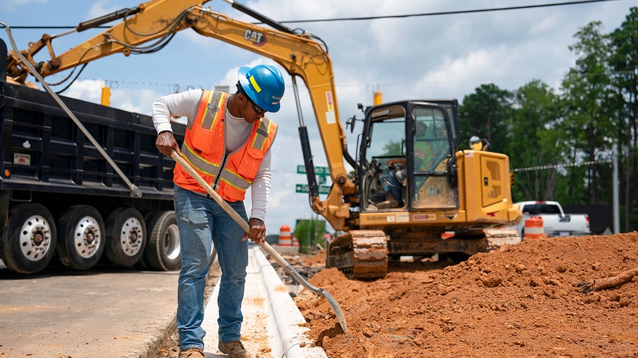 Construction worker uses shovel on road