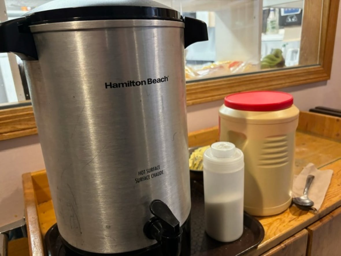 A table with a large pot of coffee, milk and sugar.  