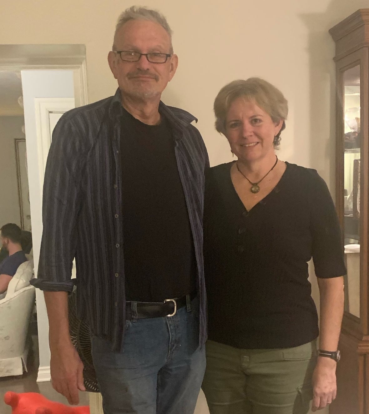 A man and a woman pose in a living room.