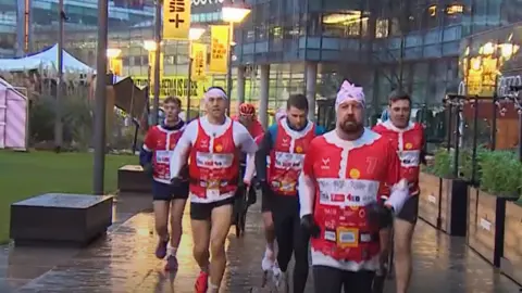 BBC Sinfield in a Christmas-themed running vest jogs with fellow runners in Salford