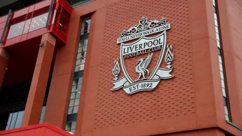 Getty Images An view of the Liverpool FC club crest on the wall of Anfield stadium, which contains the motto "You'll Never Walk Alone" and the club's founding date of 1892