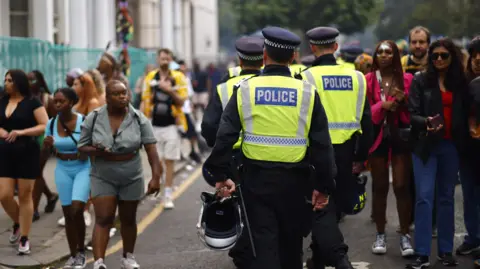 EPA Uniformed police officers walking through a small crowd of people at the carnival