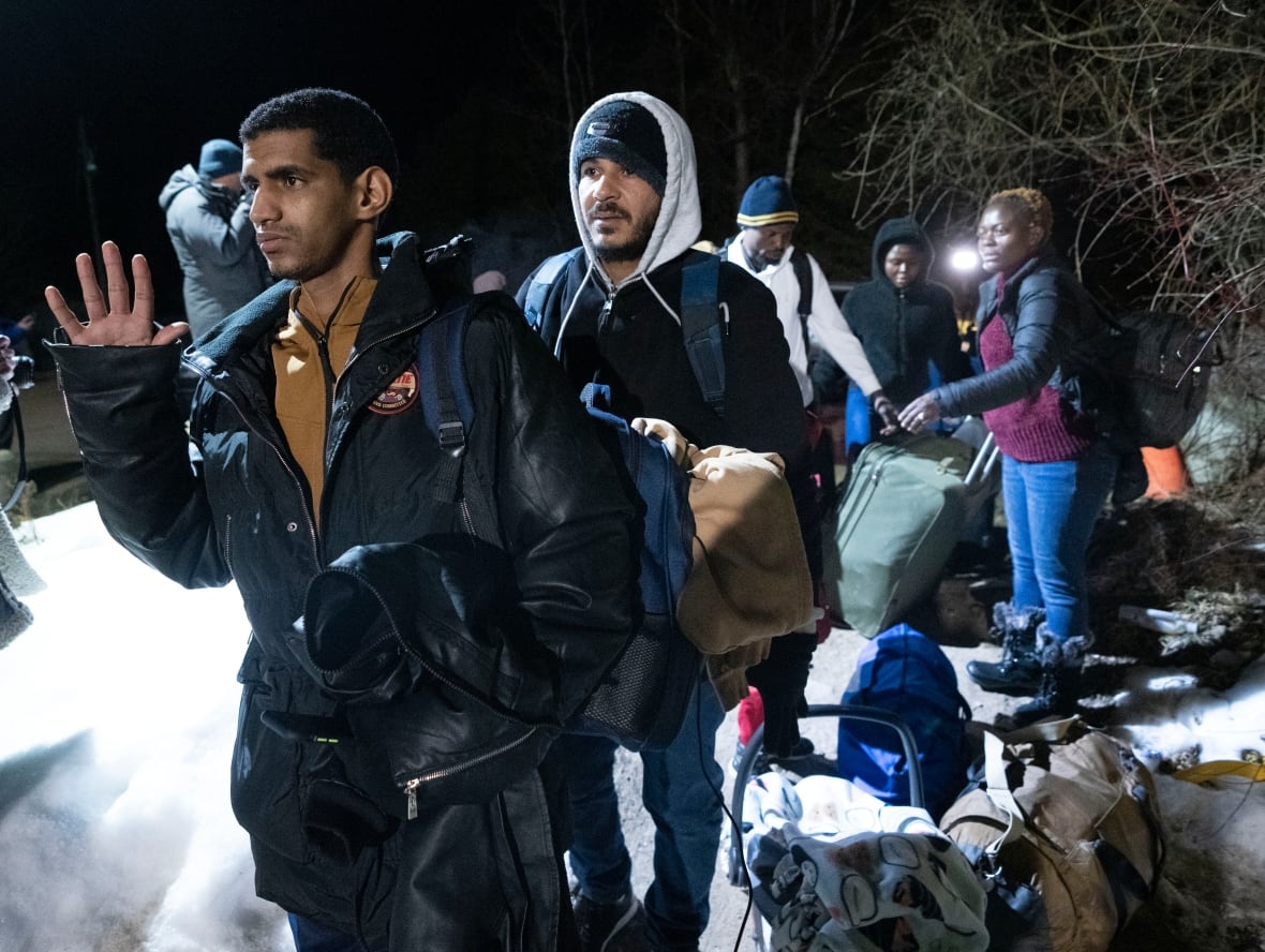 Asylum seekers cross the border at Roxham Road from New York into Canada Friday March 24, 2023, in Champlain, N.Y.