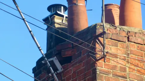 Angela Clarke Bricks have been pulled out of a chimney and an aerial is coming away from the structure after damage caused by a storm. The picture has been taken after severe weather and shows a clear, blue sky.