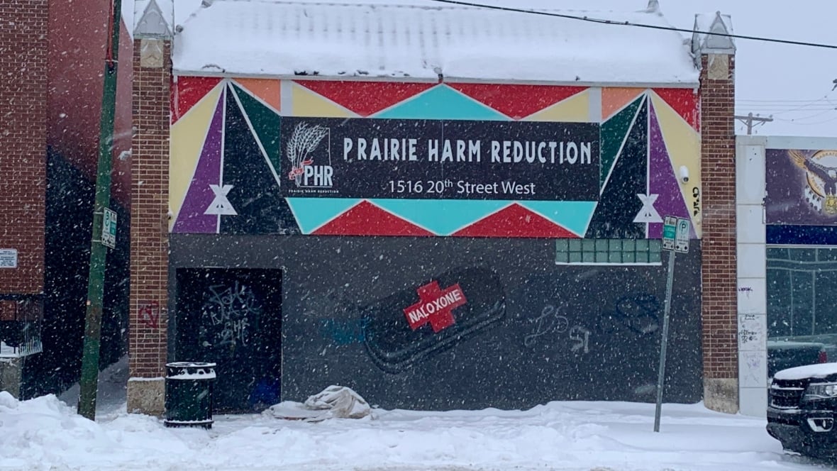 Snow falling on building with Prairie Harm Reduction sign.