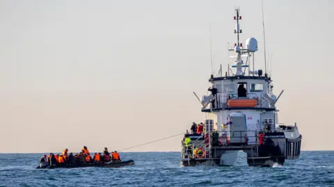 Getty Images A small boat packed with people is rescued in English waters by Border Force vessel