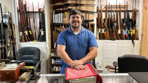 BBC James Rabun in his family's gun store, surrounded by different kinds of guns