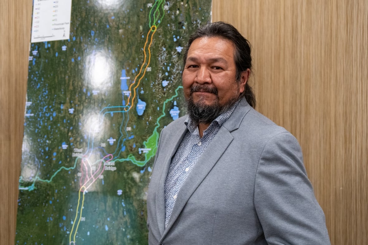 A man stands in front of a poster of a map.