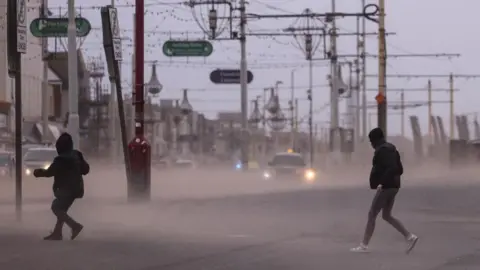 Reuters People walking through a storm in Blackpool