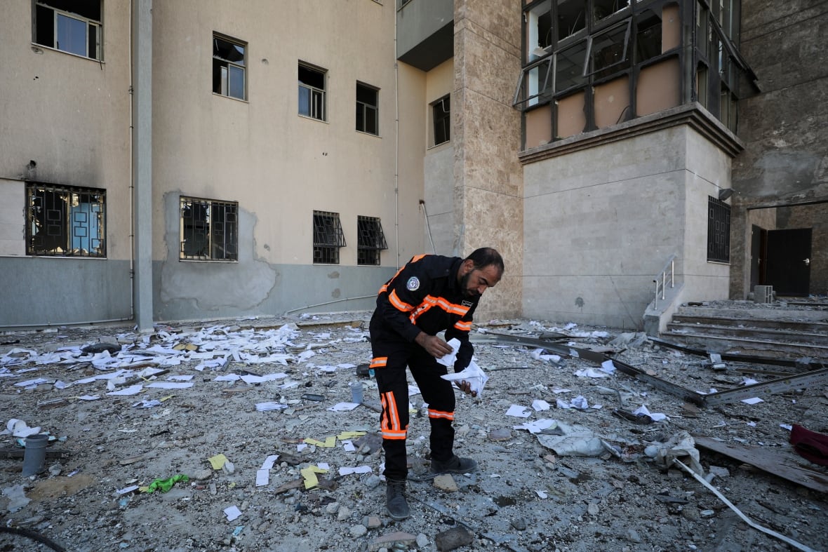 A man looks at papers on the ground at the site of an airstrike.