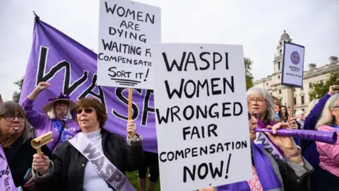 Getty Images Protesters from the Women Against State Pension Inequality (Waspi) group demonstrate outside Parliament in London. They are wearing purple sashes and holding signs reading: "Waspi women wronged, fair compensation now!" and "Women are dying waiting for compensation - sort it!"